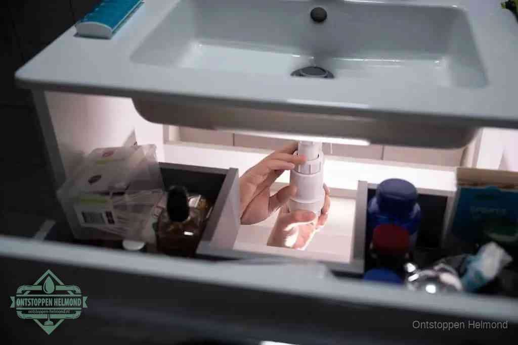 Een pompfles met zeep boven een wastafel, de heet water en afwasmiddel-methode om een vetprop in de afvoer los te maken in Helmond