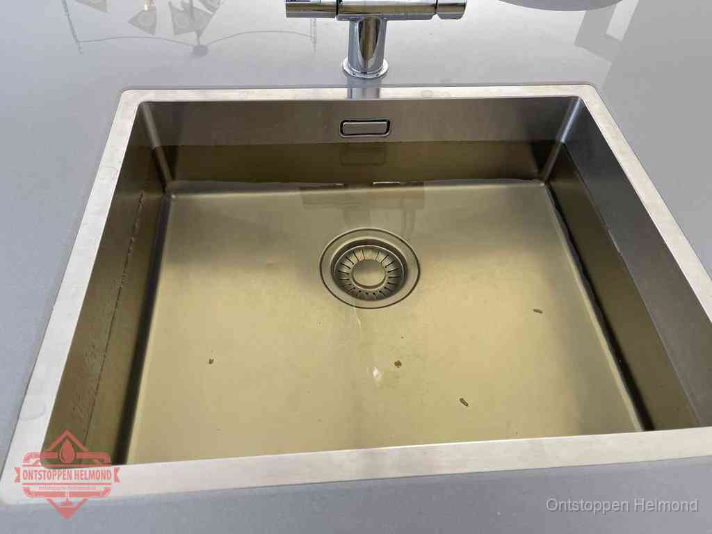 Stilstaand water in een rvs spoelbak dat niet wegloopt, een duidelijk signaal van een gootsteenverstopping in Helmond