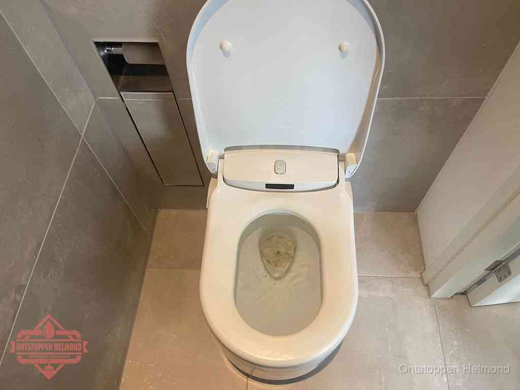 Een wit hangtoilet waarin een prop wc-papier op het water blijft drijven, een duidelijk signaal van een verstopte wc in Helmond