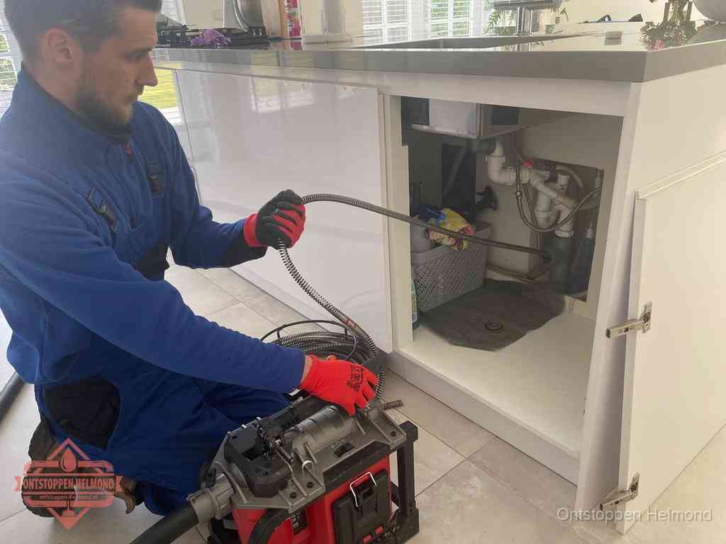 Een monteur reinigt de keukenafvoer grondig met een veermachine om terugkerende gootsteenverstoppingen te voorkomen in Helmond