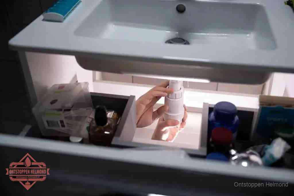 Een pompfles met zeep boven een wastafel in de toiletruimte, de warm water en afwasmiddel-methode om de wc te ontstoppen in Helmond