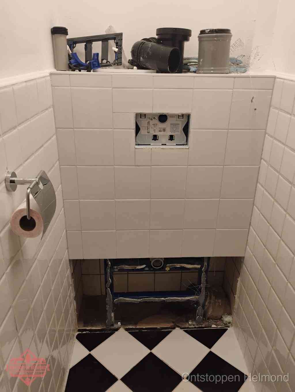 Een toiletruimte waar het hangtoilet en de inbouwreservoir-onderdelen zijn vrijgelegd voor onderhoud, periodiek nazicht voorkomt een wc-verstopping in Helmond