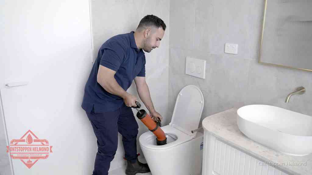 Een monteur gebruikt een handmatige perspomp (toiletontstopper) op een wandcloset tijdens het professioneel wc ontstoppen in Helmond